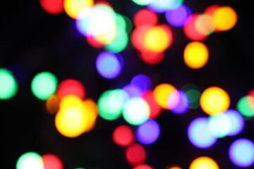 Fototapeta premium Blurred view of bright Christmas lights on dark background, bokeh effect