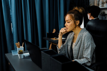 Serious face of thinking businesswoman focusing computer to report data analysis social media online project job with coworker working at back side at over late night time at modern office. Infobahn.