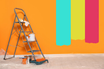 Decorator's stuff in room near wall partly painted in different shades. Choosing color for interior