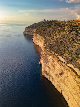 Vertical aerial view of Dingli Cliffs at sunset. Majestic limestone cliffs and Mediterranean sea horizon in Malta.
