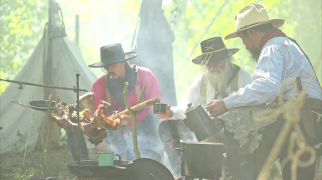 Group of cowboys preparing food at a campfire, roasting meat together in a warm and rustic outdoor setting