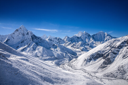 Himalaya mountains in sunny day after snowfall. Mt. Ama Dablam, Thamserku and others behind snow covered slopes between Thokla (Dughla) and Dingboche in Nepal. Aerial view from the helicopter.