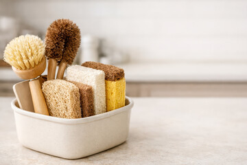 Natural cleaning brushes and sponges in container on kitchen countertop, eco friendly tools for household chores with soft bristles and textured surfaces for effective cleaning