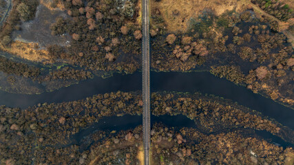 Aerial straight two lane bridge over winding river in Belarus winter