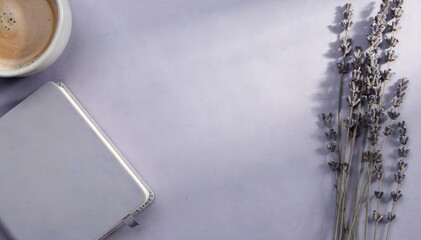Aesthetic flat lay with a purple notebook, dried lavender, and a cup of coffee on a soft lavender background.