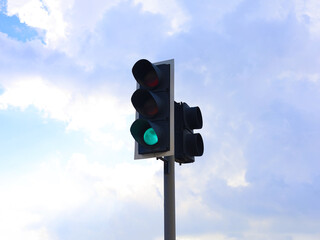Green traffic light against blue sky