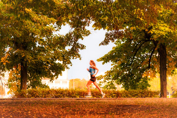 Woman in motion blur running in autumn park