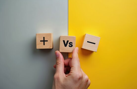 Wooden cubes show plus versus minus symbols. Hand places Vs block between positive and negative sides. Decision making concept of choice and balance between good and bad options.