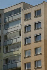 Fototapeta premium In this image, you can see a multistory apartment building, showcasing a variety of balconies and distinctive window arrangements that are noticeable on its two different facades