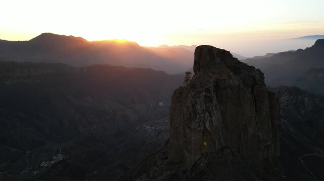 Cinematic drone flight over the volcanic peaks of Gran Canaria featuring the iconic Roque Bentayga monolith during a dramatic golden hour sunset - UNESCO site