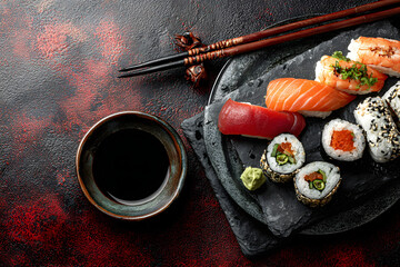 flat lay with soya sauce in bowl, chopsticks and nigiri sushi set on black slate plate on red and black background