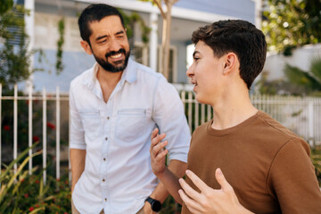 Teenage son speaks while his father listens attentively during an outdoor walk, highlighting active listening, empathy, guidance, emotional awareness, and family wellbeing