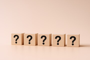 Five Wooden Blocks Displaying Black Question Marks, Representing Uncertainty and Inquiry on Beige Background