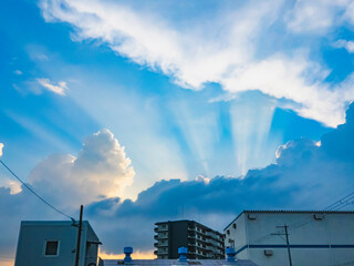 天使の梯子とドラマチックな夏の雲、空を見上げる建物