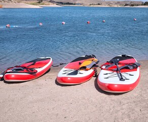 Three SUP boards on a sandy beach near the water
