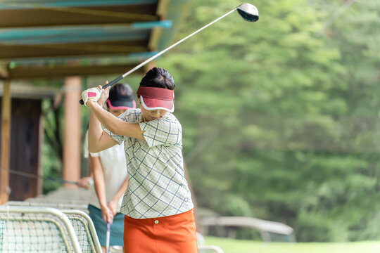 Golf player practicing swing at golf driving range, driving range, golf center, female golfer