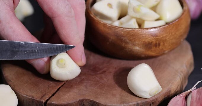 peeled purple garlic scattered on the black kitchen table and peeled and sliced, fragrant fresh and natural garlic spices scattered on the kitchen table during cooking
