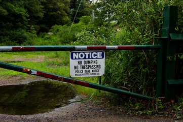 Fototapeta premium Security Warning: Notice Sign Restricting Trespassing and Dumping on Private Property Through Secure Gate in Rural Area
