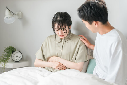 Woman with abdominal pain and worried man (bedroom, menstrual pain, morning sickness)