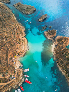 High angle aerial view of Blue Lagoon in Comino island, turquoise crystal clear water and luxury yachts on the coast of Malta, 4K drone