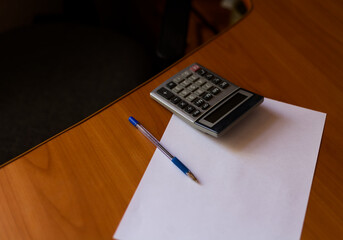 Office Desk Essentials: Calculator, Pen, and Paper on Wooden Workspace for Financial Planning and Calculation Tasks