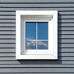 A white framed window reflects blue sky and clouds in a gray horizontal wooden plank wall of a building