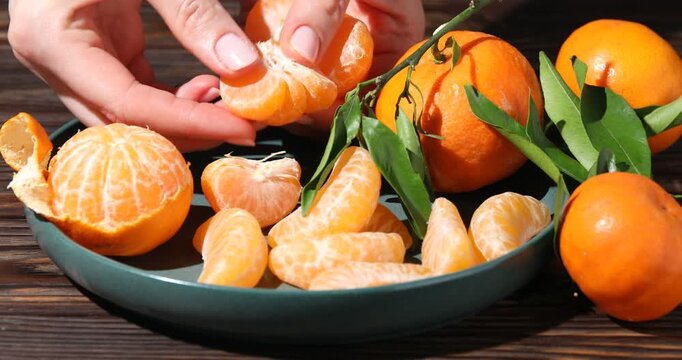 Woman with ripe tangerines at wooden table, closeup