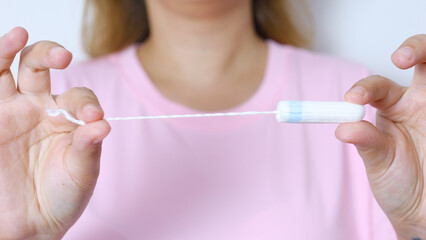 Woman holding medical tampon, demonstrating feminine hygiene product for menstrual care and women's health