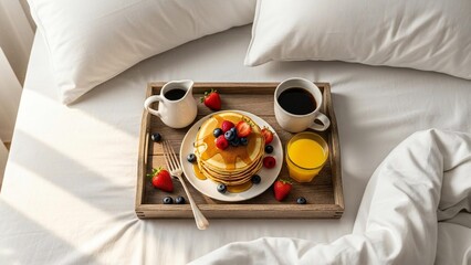 A delicious breakfast spread on a wooden tray in bed with pancakes and fresh fruit