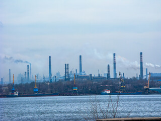 White smoke billowing out from factory tall pipes as seen across fright port on left bank of Dnipro river in industrial city of Zaporizhzhia, Ukraine