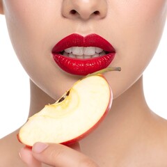 A woman holding an apple slice near her face with bright red lipstick, close-up on white