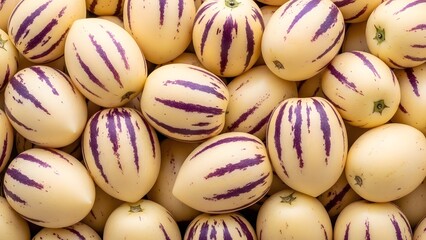 A close-up of fresh Pepino melons (Solanum muricatum) with smooth cream-colored skin and distinctive purple stripes, arranged in a dense group