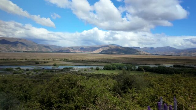 Panoramic valley view with braided river and mountains under blue sky