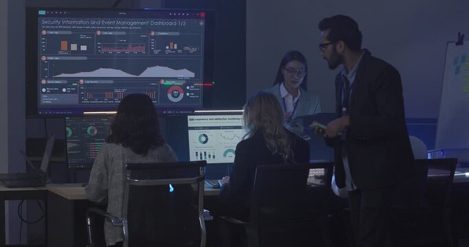 A focused team wearing headsets monitors live analytics dashboards and collaborates in modern control room. Highlighting customer support, data driven decision making, coordinated incident response.
