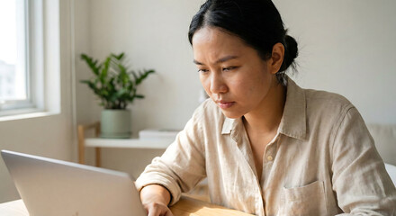 Young ambitious asian girl working remote from home, looking at laptop screen and smiling. Woman checking mail or researching while telecommuting, sitting on floor at her apartment