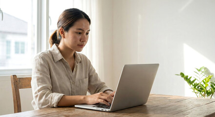 Young ambitious asian girl working remote from home, looking at laptop screen and smiling. Woman checking mail or researching while telecommuting, sitting on floor at her apartment