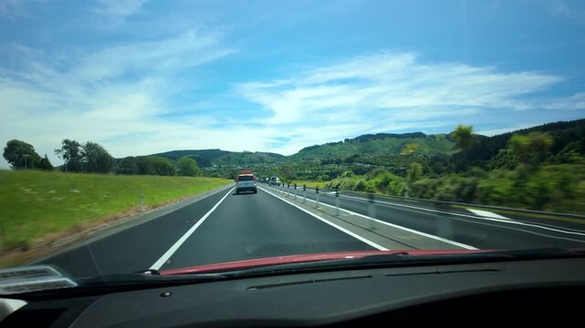 Driving on New Zealand highway through green hills from car interior