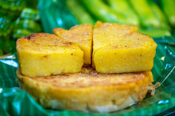 Baked sweet cassava cake served in slices on green banana leaves.
