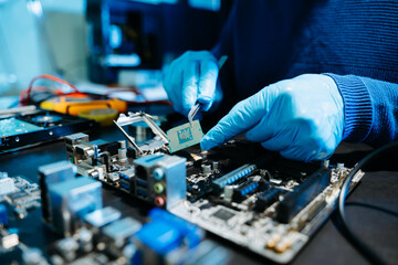 The technician is putting the CPU on the socket of the computer motherboard. electronic engineering electronic repair, electronics measuring