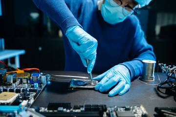 Closeup of expert soldering a green PCB board using precision tools. Ideal for electronics, circuit repair, engineering, tech
