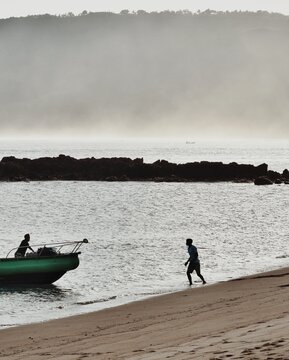 A person is walking on the beach, heading for a boat in Lombok