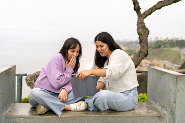 Two young women sharing content on a tablet outdoors