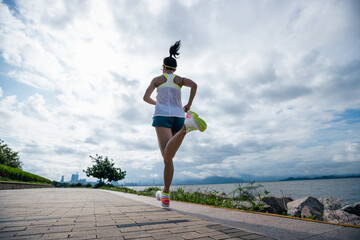 Fitness woman running training for marathon on sunny coast trail