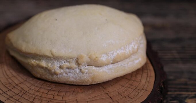 a whole fresh shortbread bun with cottage cheese filling on a wooden board on the table, soft pastries stuffed with cottage cheese and sugar are on the board