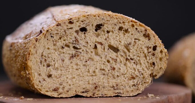 sliced fresh loaf of bread on black slate, freshly baked soft loaf of rye bread cut in half