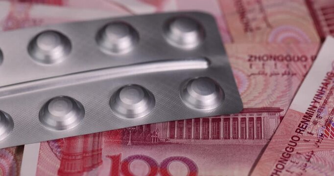 Chinese cash for one hundred yuan and pills in a packaged blister, medicines and red Chinese cash with a face value of 100 yuan together.