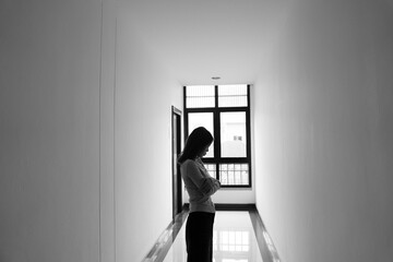 A lonely young woman sits on the floor in a narrow hallway, clutching her head in despair, expressing sadness, stress, and emotional conflict in the quiet, simple interior of the building. The image i