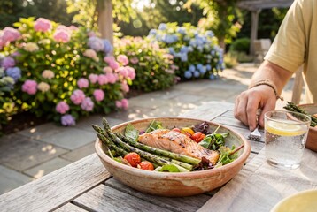 Grilled salmon with asparagus and salad served on a wooden table during a sunny summer lunch outdoors
