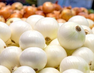 Close-up of white onions in a pile, with brown onions blurred in back