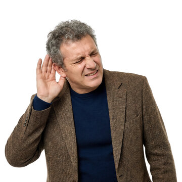 Mature man with hearing difficulty, cupping ear and squinting in discomfort on white background, portrait style, healthcare concept, noise